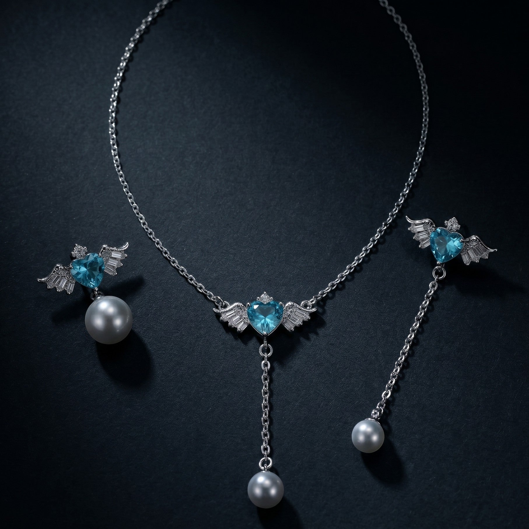SVORA Angel Aqua Asymmetric Necklace Earrings Set with blue heart crystals, pearl drops, and silver wings.