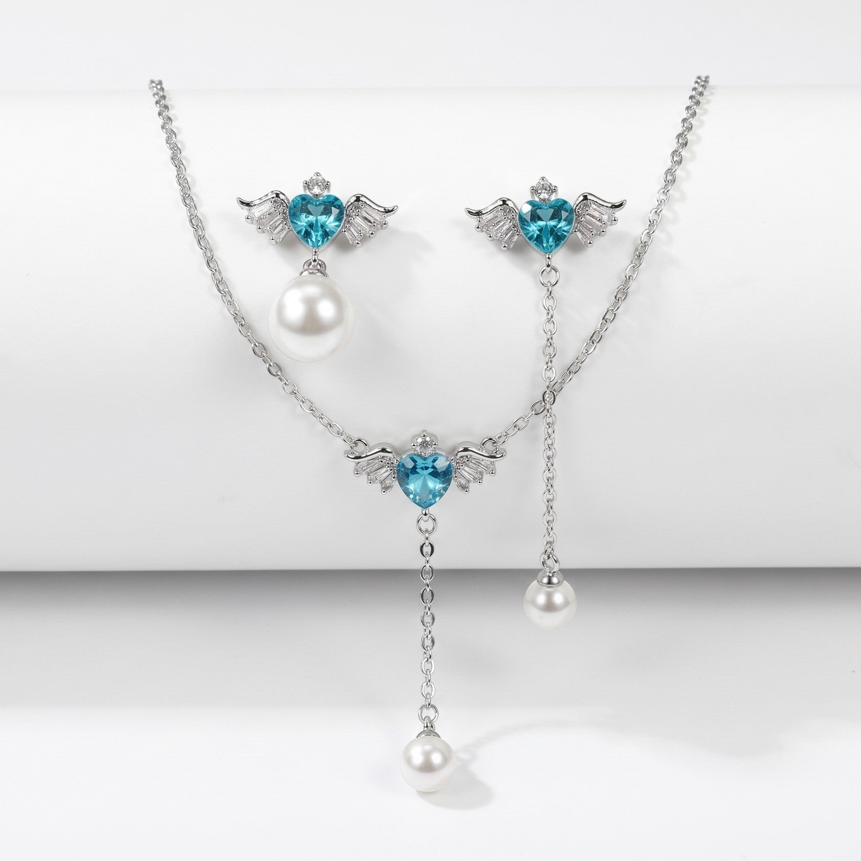 SVORA Angel Aqua Asymmetric Necklace Earrings Set with blue crystal hearts, pearl drops, and silver-tone finish.