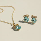 SVORA gold-tone necklace and earrings set with aqua cushion-cut crystals and pavé bow details.