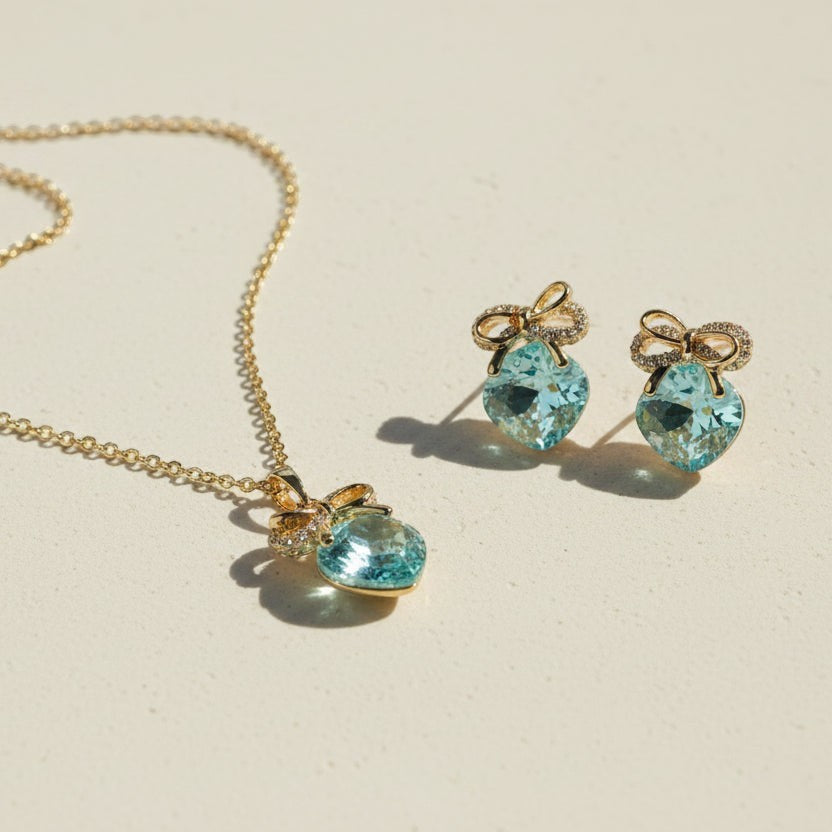 SVORA gold-tone necklace and earrings set with aqua cushion-cut crystals and pavé bow details.