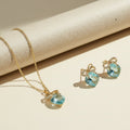 SVORA gold-tone necklace and earrings set with aqua cushion-cut crystals and pavé bow details.