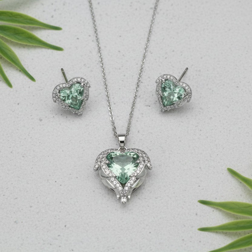 SVORA aqua heart necklace and earrings set with pavé wings and crown detail, made of stainless steel and cubic zirconia.