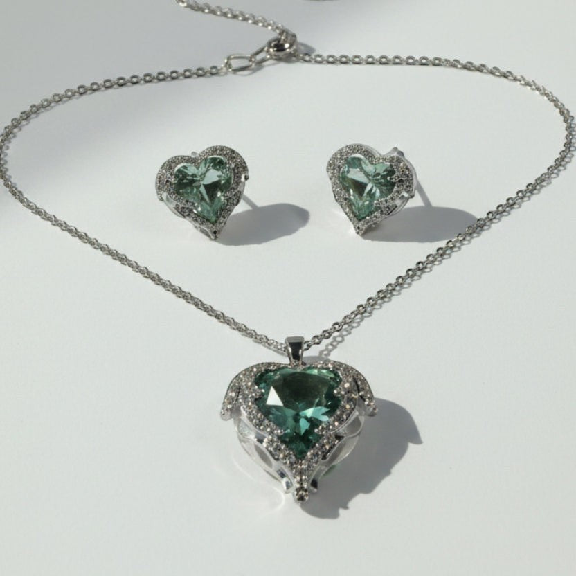 SVORA aqua heart necklace and earrings set with silver-tone pavé wings and crown detail. Features aqua crystal cubic zirconia.