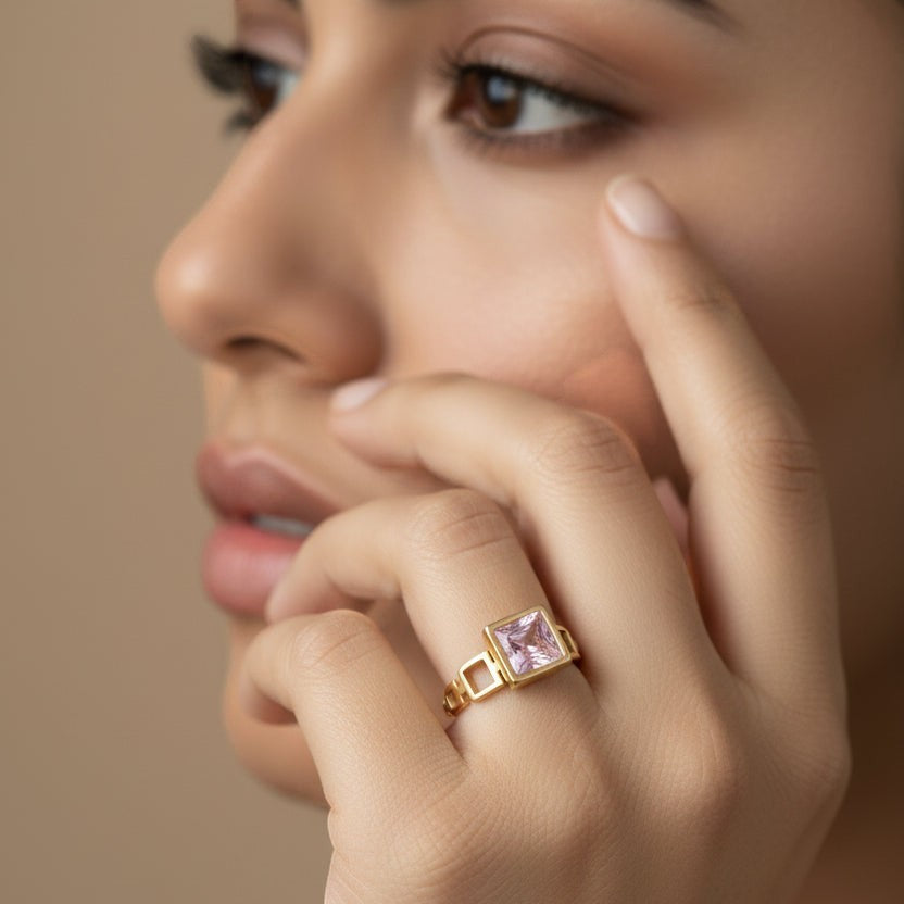 SVORA gold tone ring with a square-cut blush pink stone and geometric links. 18K gold plated stainless steel.