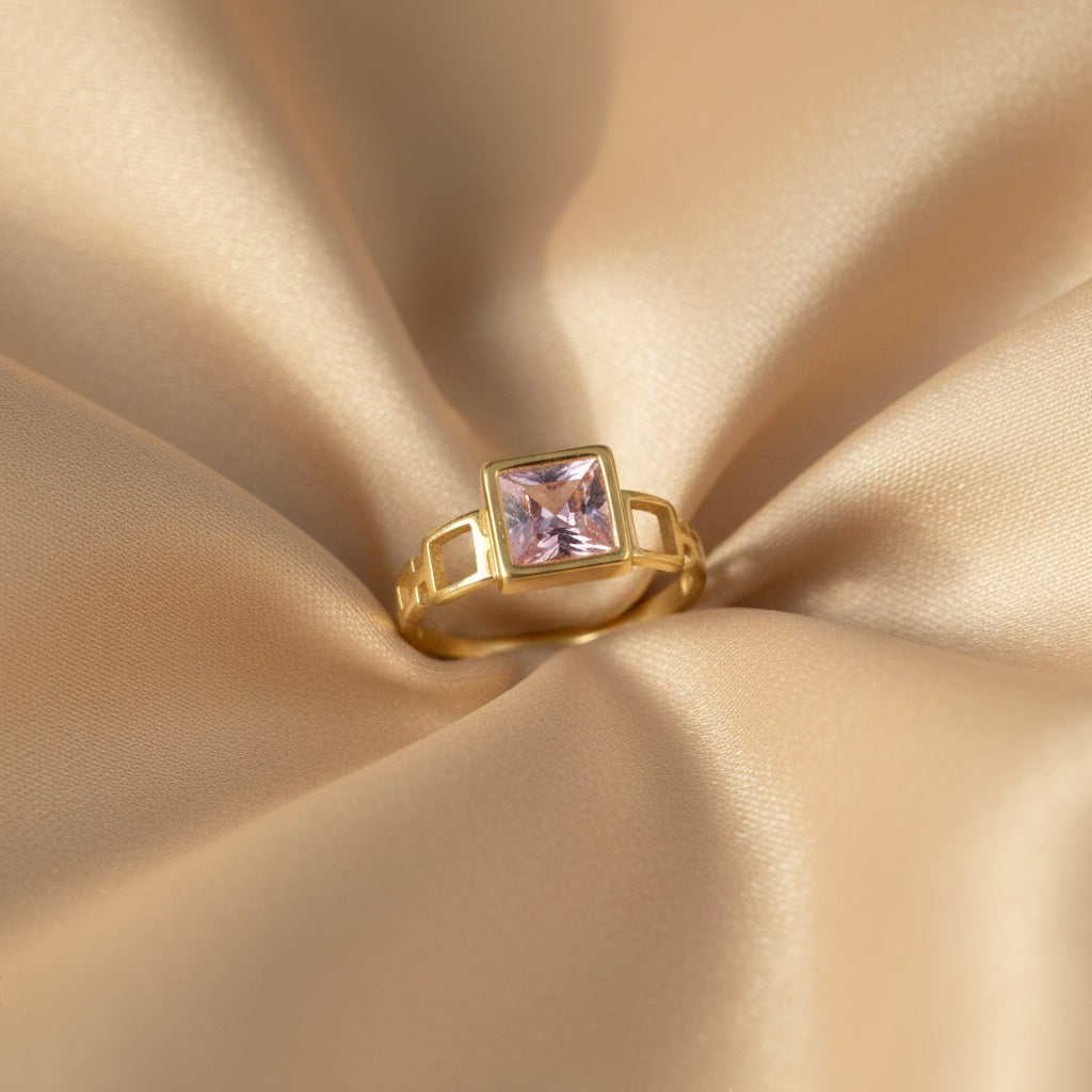 SVORA gold-tone ring with a square-cut blush pink stone and geometric side details. 18K gold plated.