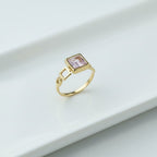 SVORA gold tone ring with a blush pink square-cut stone and geometric open links. 18K gold plated.