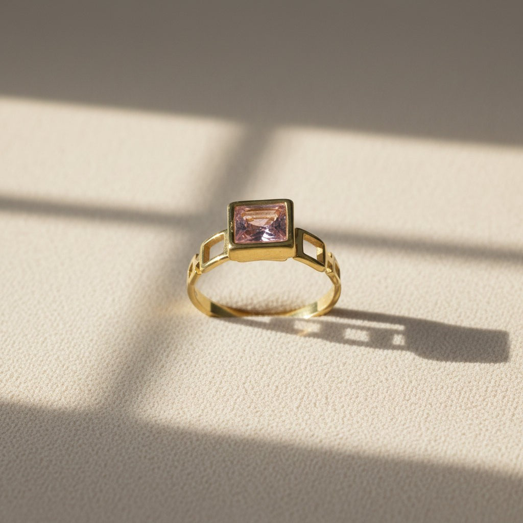 SVORA gold-tone ring with a square-cut blush pink stone and geometric cut-outs on the band. 18K gold plated.