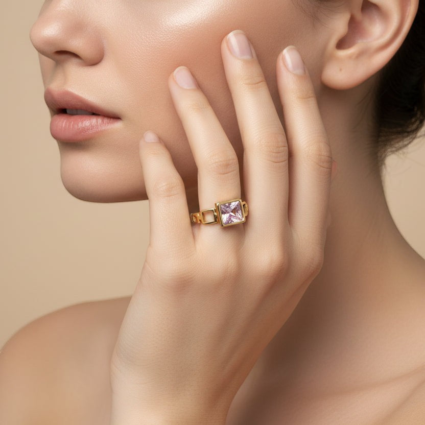 SVORA gold-tone ring with a square-cut blush pink stone and open square link band. Modern Deco style.