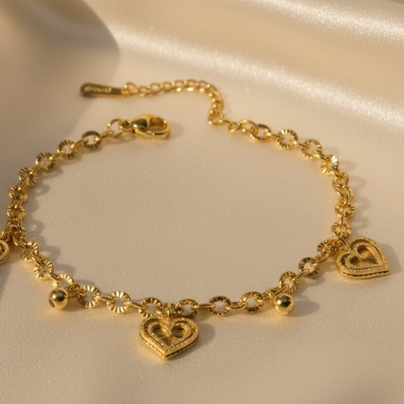 SVORA gold cable chain bracelet with three heart charms and gold beads. 18K gold plated stainless steel.