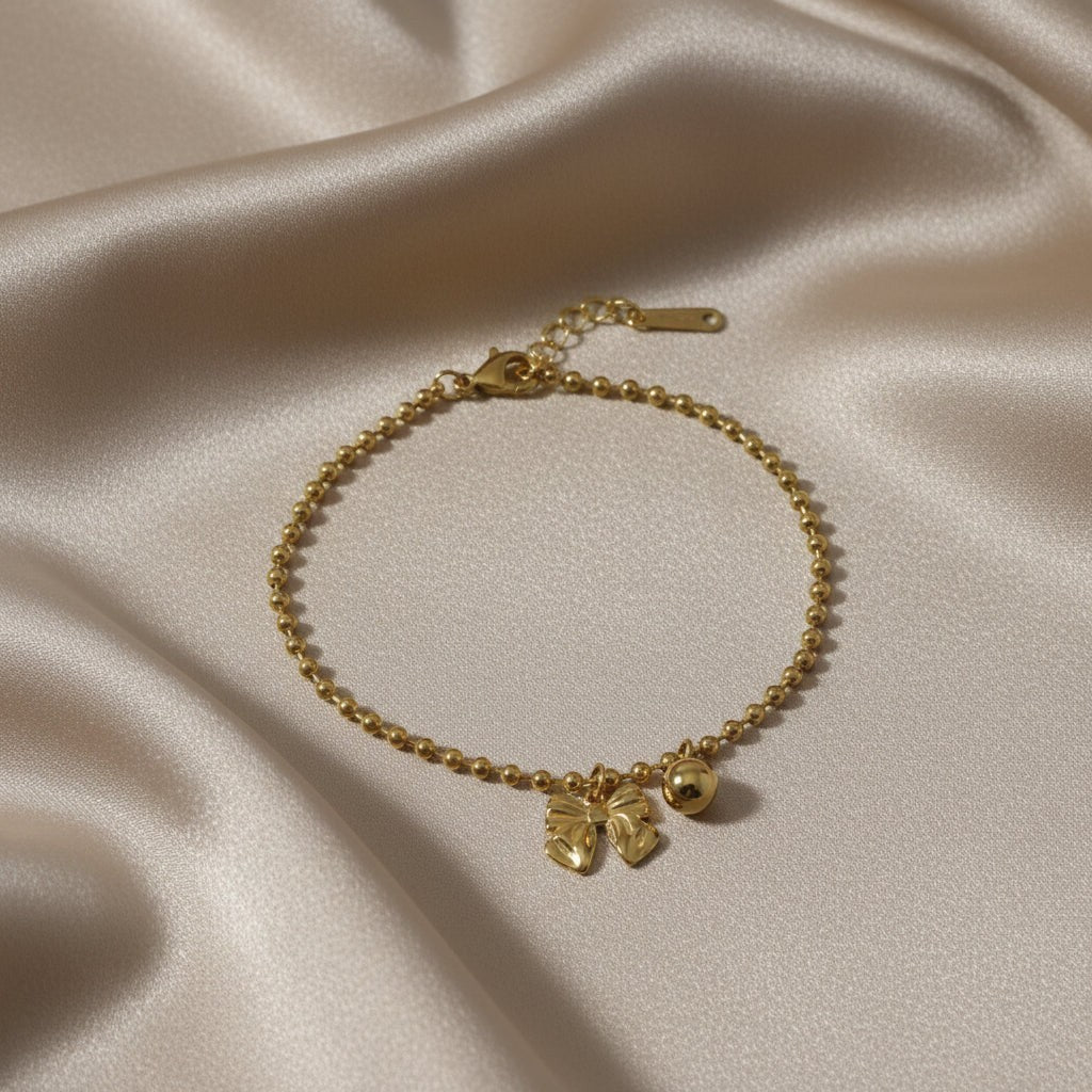 SVORA gold-plated stainless steel bracelet with a bow charm and ball bead chain. Adjustable with lobster clasp.