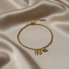 SVORA gold-plated stainless steel bracelet with a bow charm and ball bead chain. Adjustable with lobster clasp.