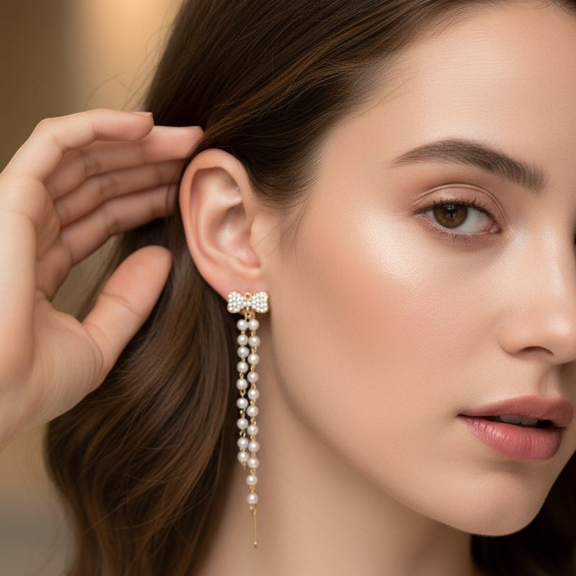 SVORA gold tone bow pearl dangler earrings with cubic zirconia and freshwater-style pearls.