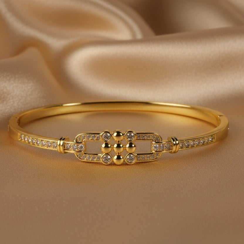 SVORA gold-plated stainless steel bangle bracelet with buckle detail and cubic zirconia stones.
