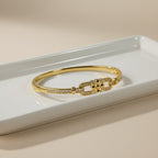SVORA gold-plated stainless steel bangle bracelet with buckle cluster and CZ stones.