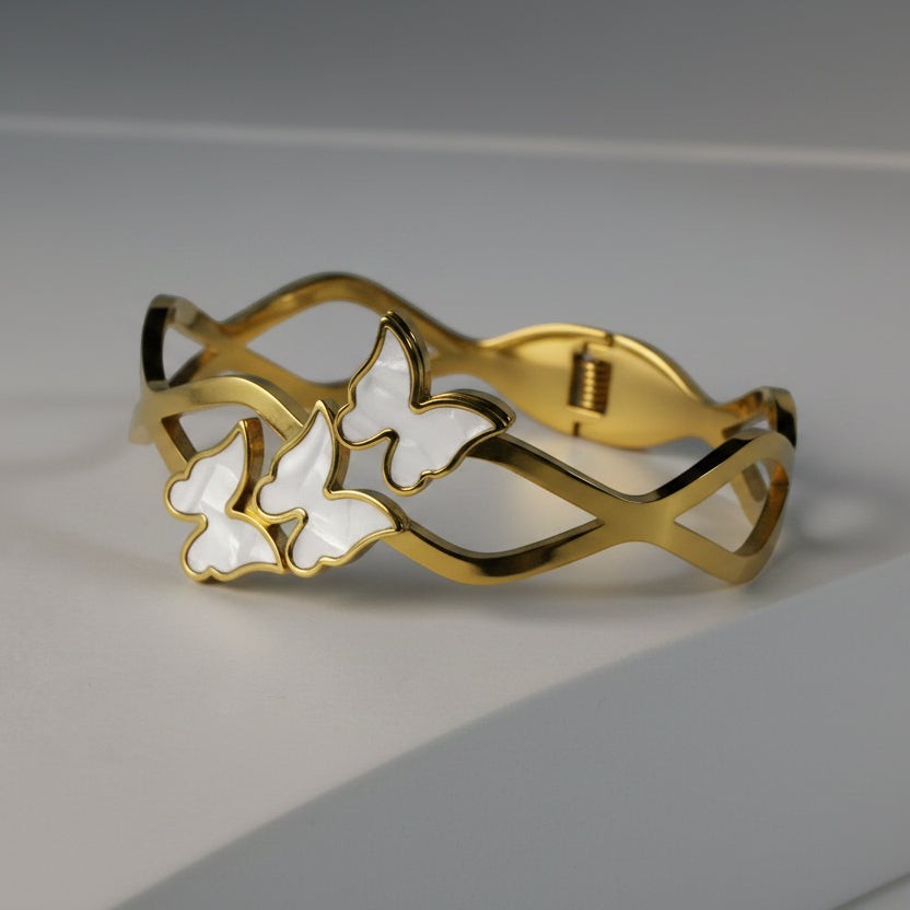 SVORA gold-plated stainless steel bracelet with three mother-of-pearl butterflies and a wave-edged band.