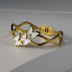 SVORA gold-plated stainless steel bracelet with three mother-of-pearl butterflies and a wave-edged band.