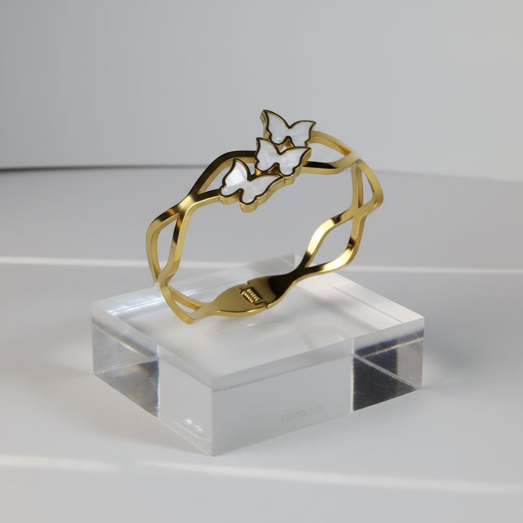 SVORA gold-plated stainless steel bracelet with three mother-of-pearl butterflies, wave-edged band.