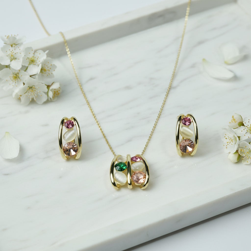 SVORA gold tone necklace and earrings set with pink, green, and cream cabochon stones in a caged design.