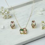 SVORA gold tone necklace and earrings set with pink, green, and cream cabochon stones in a caged design.
