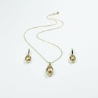 SVORA oval champagne crystal necklace and earrings set in polished gold with curved framing detail.