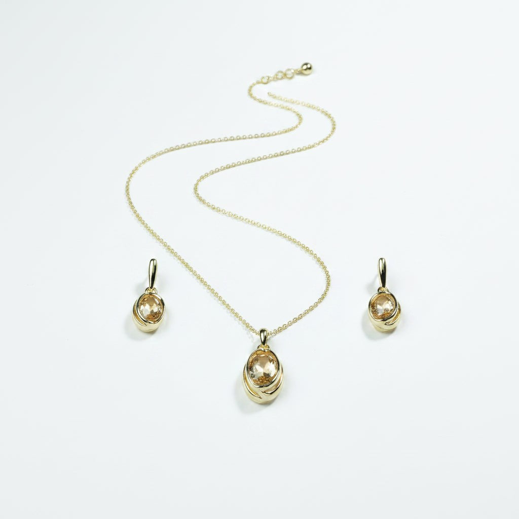 SVORA oval champagne crystal necklace and earrings set in polished gold with curved framing detail.