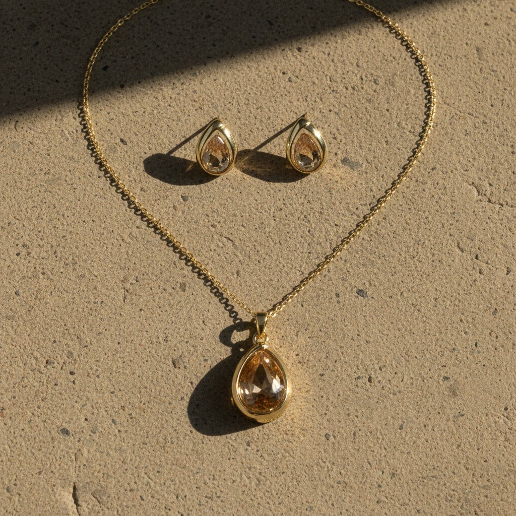 SVORA champagne pear-cut crystal pendant necklace and matching earrings set in polished gold.