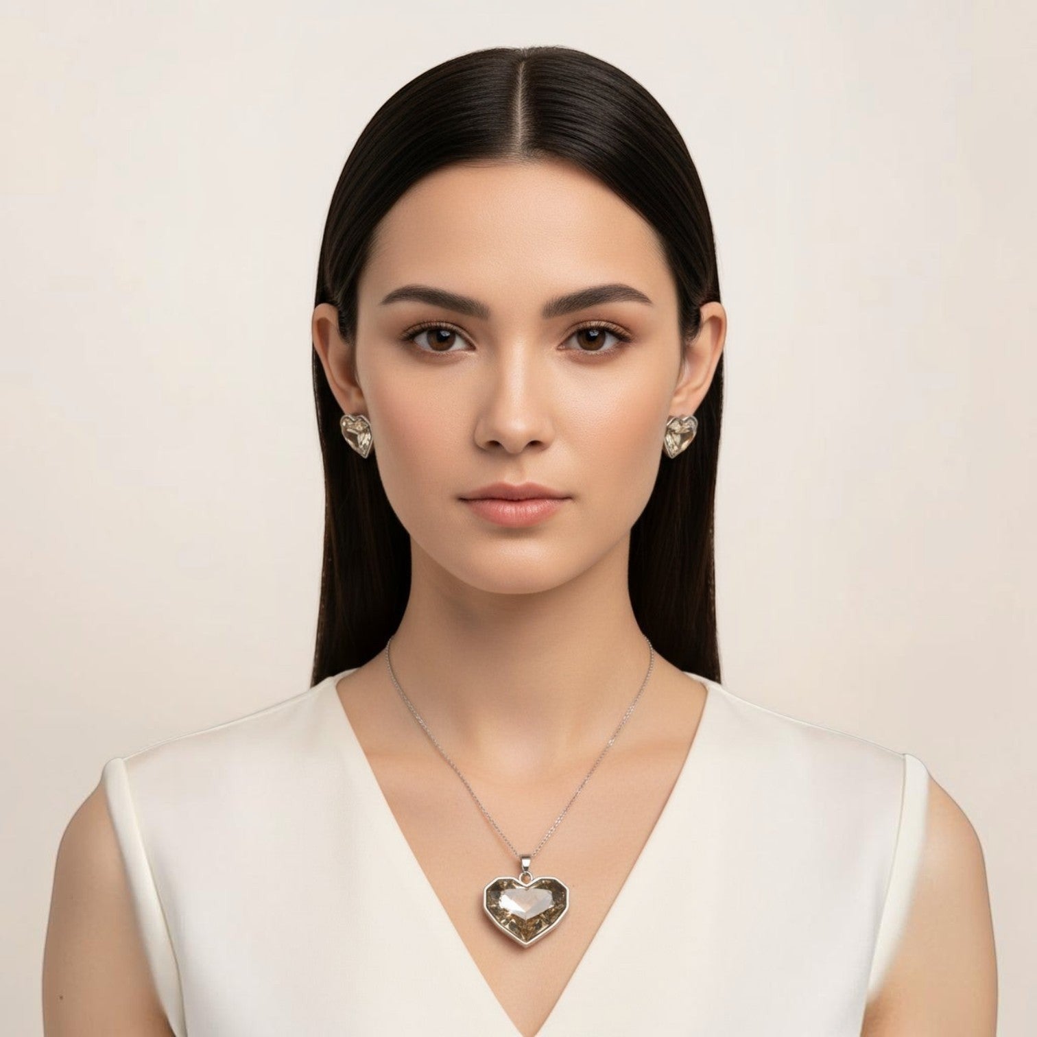 SVORA champagne crystal heart necklace and earrings set with silver bezels. Model wears a white dress.