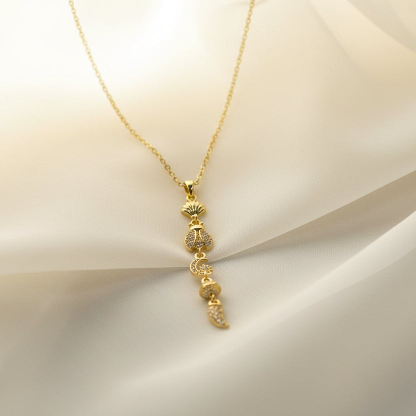 SVORA gold plated stainless steel lariat necklace with shell, bee, moon, heart, and leaf charms.