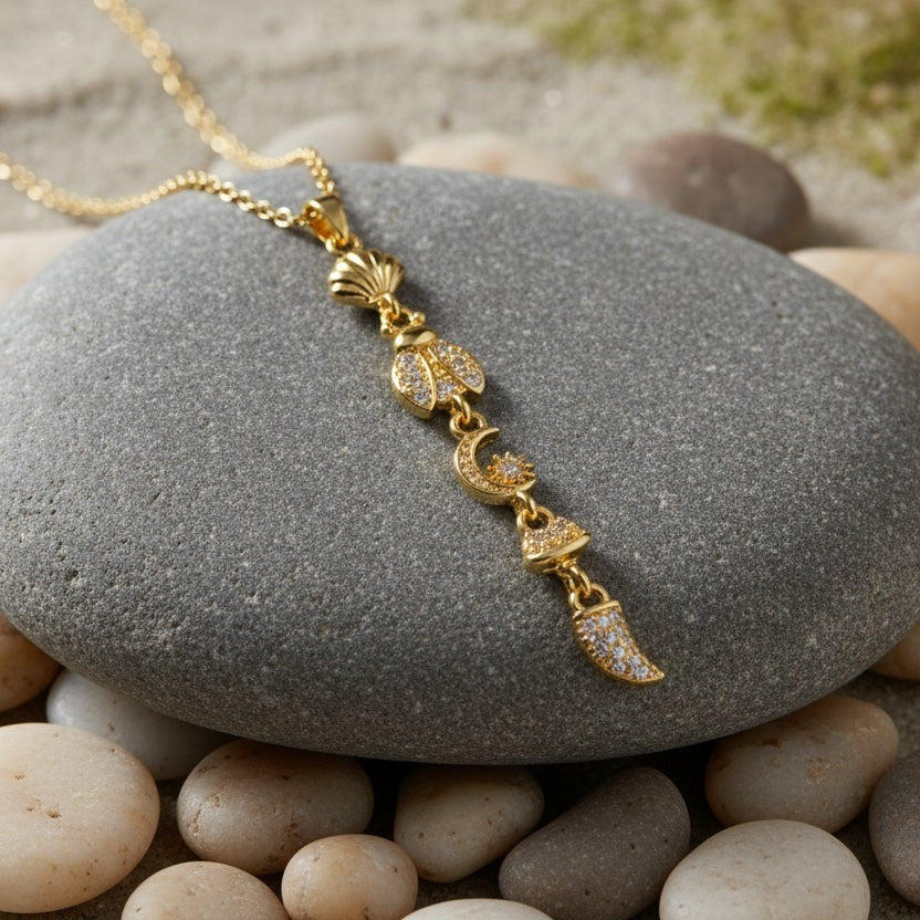 SVORA gold plated stainless steel necklace with shell, bee, moon, and horn charms.