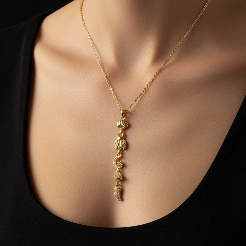 SVORA gold plated stainless steel necklace with shell, ladybug, moon, and horn charms.