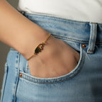 SVORA gold plated stainless steel bracelet with two connected hearts, one solid and one open, on a fine chain.