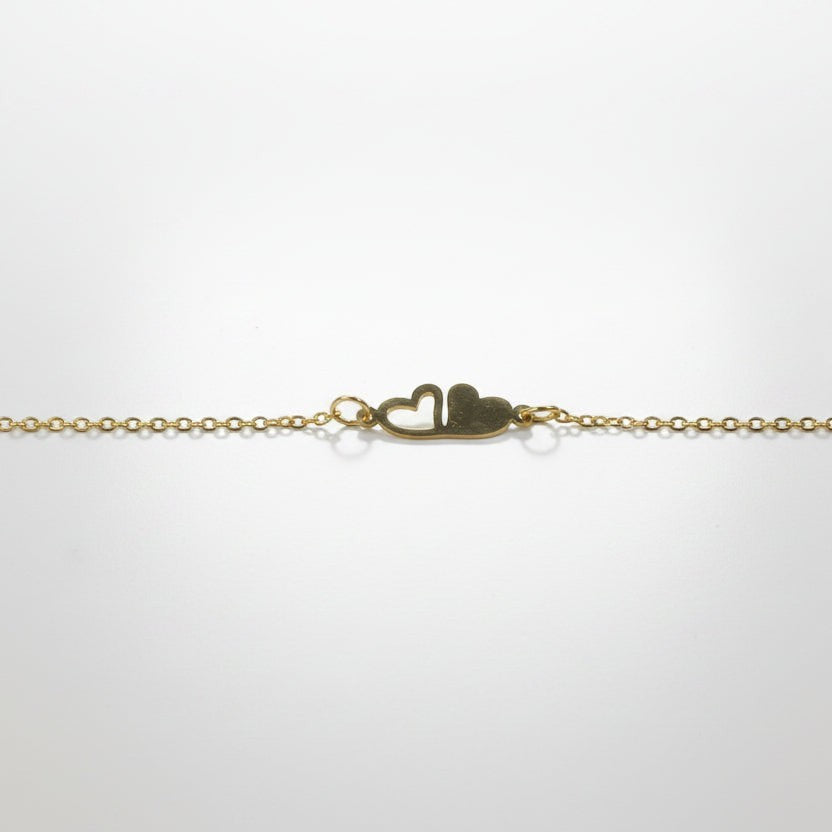 SVORA gold plated stainless steel chain bracelet with two connected hearts, one solid and one open.