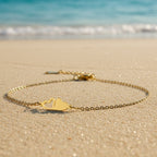 SVORA gold plated stainless steel bracelet with two connected hearts, one solid and one open, on a fine chain.
