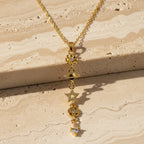 SVORA gold cable chain lariat necklace with dangling charms: daisy, Saturn, star, quatrefoil, and heart. 18K gold plated.