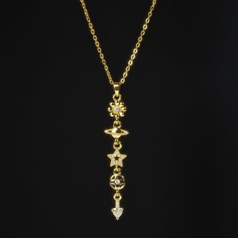 SVORA gold cable chain lariat necklace with daisy, Saturn, star, quatrefoil, and heart charms.
