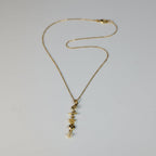 SVORA gold cable chain necklace with a vertical drop of charms including a daisy, Saturn ring, CZ star, quatrefoil, and heart.