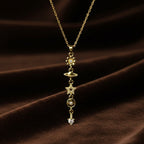 SVORA gold cable chain necklace with vertical drop of daisy, Saturn, star, circle, and heart charms.