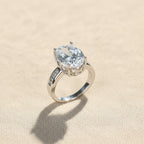 SVORA Ethereal Diamond Solitaire Ring with oval-cut clear stone and channel-set baguette band in rhodium-plated stainless steel.