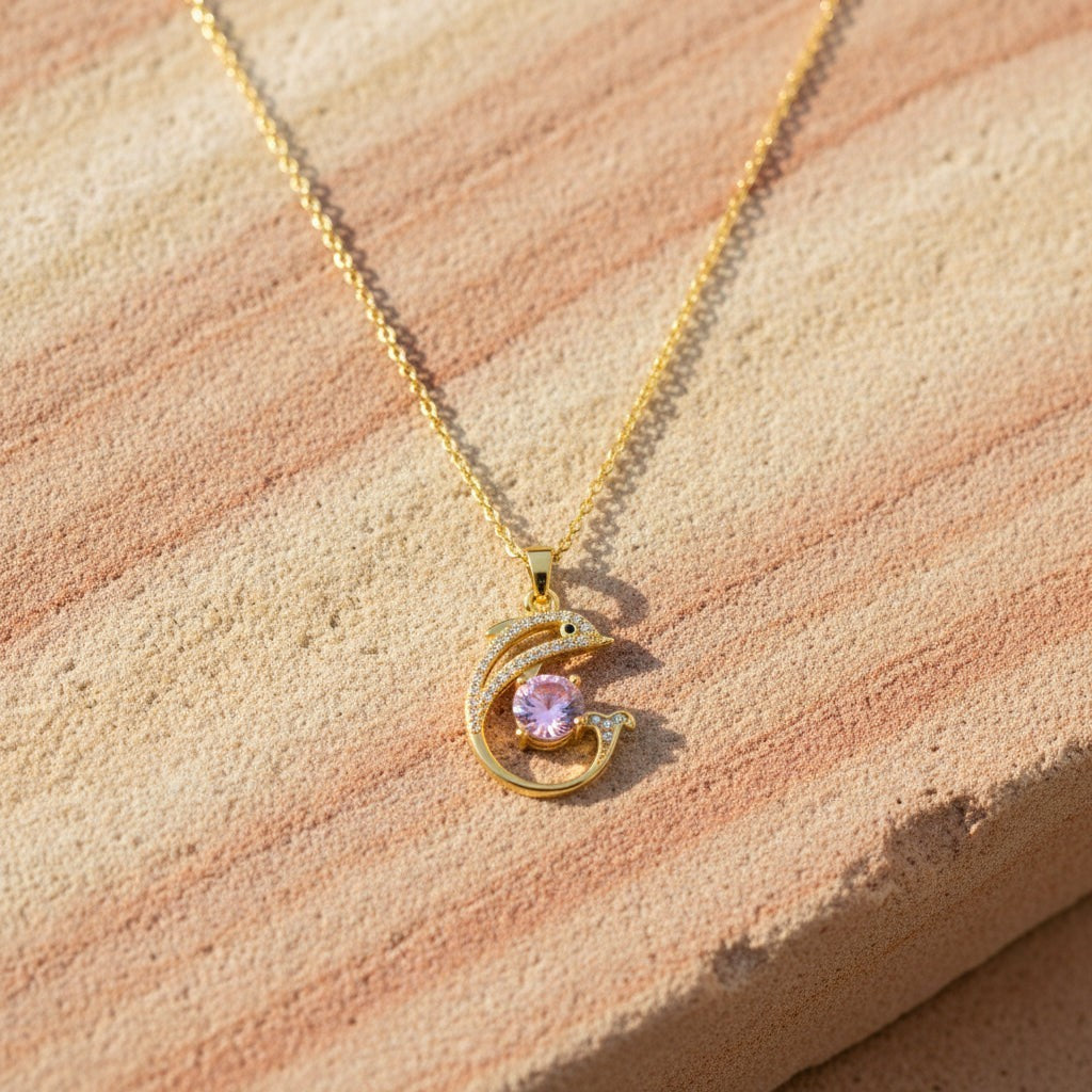 SVORA gold plated stainless steel necklace featuring a pavé dolphin pendant with a large pink CZ stone.