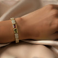 SVORA gold-tone stainless steel bracelet with pave crystals and rectangular red and green gems.