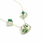 SVORA gold-tone necklace and earrings set with caged emerald and cream cabochon stones.