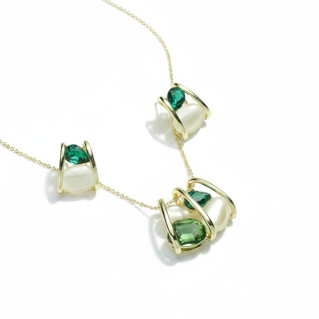 SVORA gold-tone necklace and earrings set with caged emerald and cream cabochon stones.