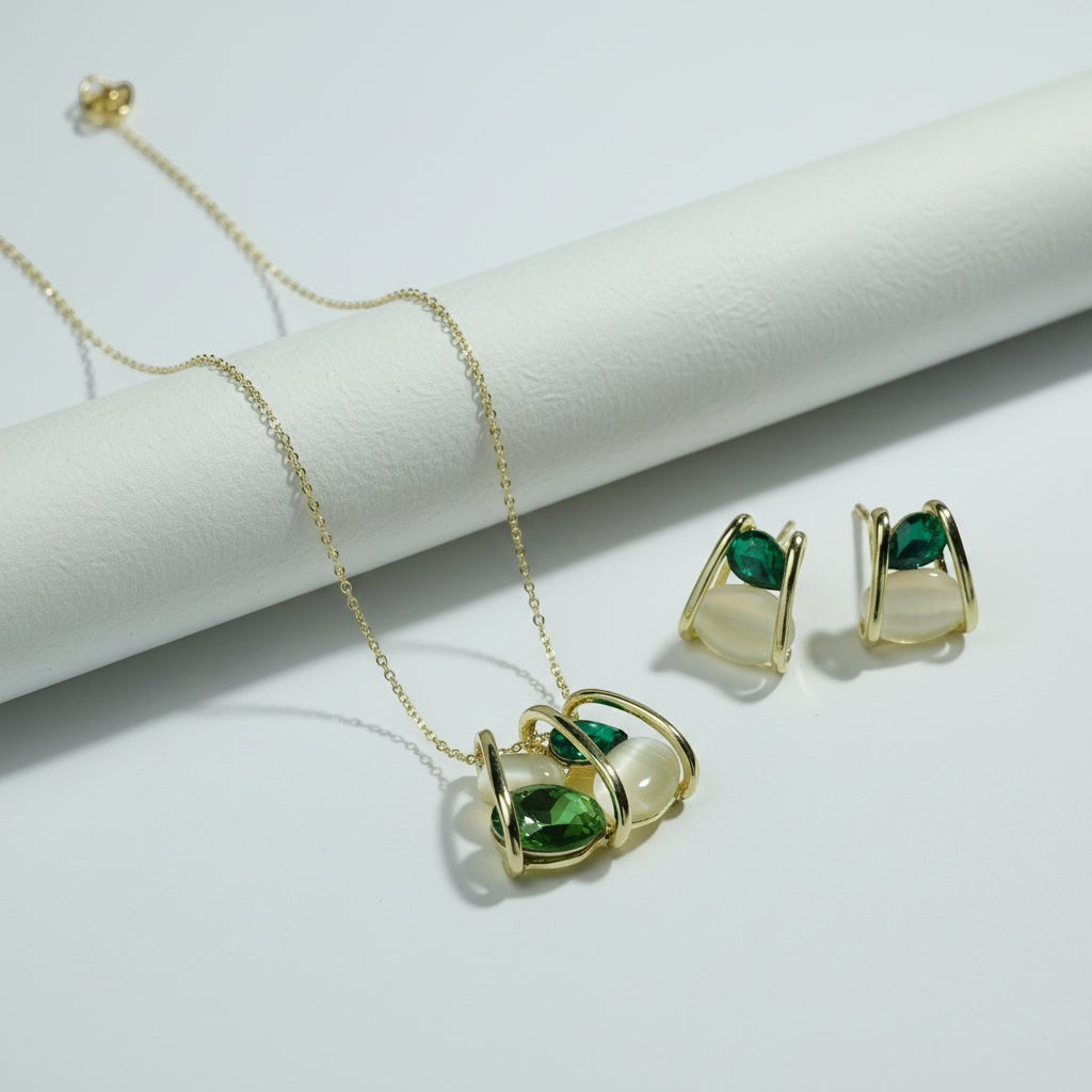 SVORA gold-tone necklace and earrings set with emerald and cream stones in a cage design.