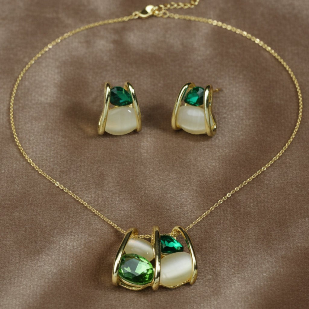 SVORA gold-tone necklace and earrings set with emerald green and cream cabochon stones in a caged design.