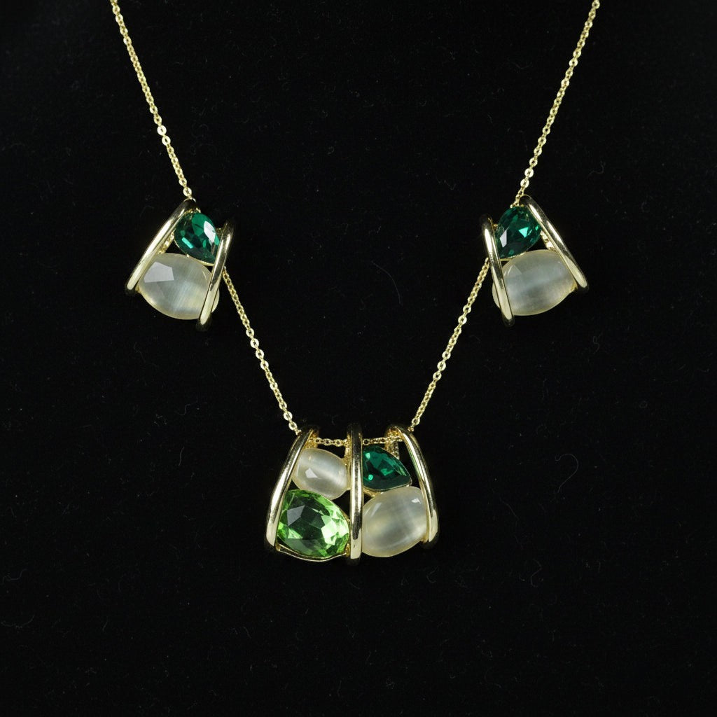 SVORA gold-tone necklace and earrings set with emerald and cream stones in a caged design.