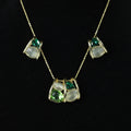 SVORA gold-tone necklace and earrings set with emerald and cream stones in a caged design.