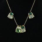 SVORA gold-tone necklace and earrings set with emerald and cream stones in a caged design.