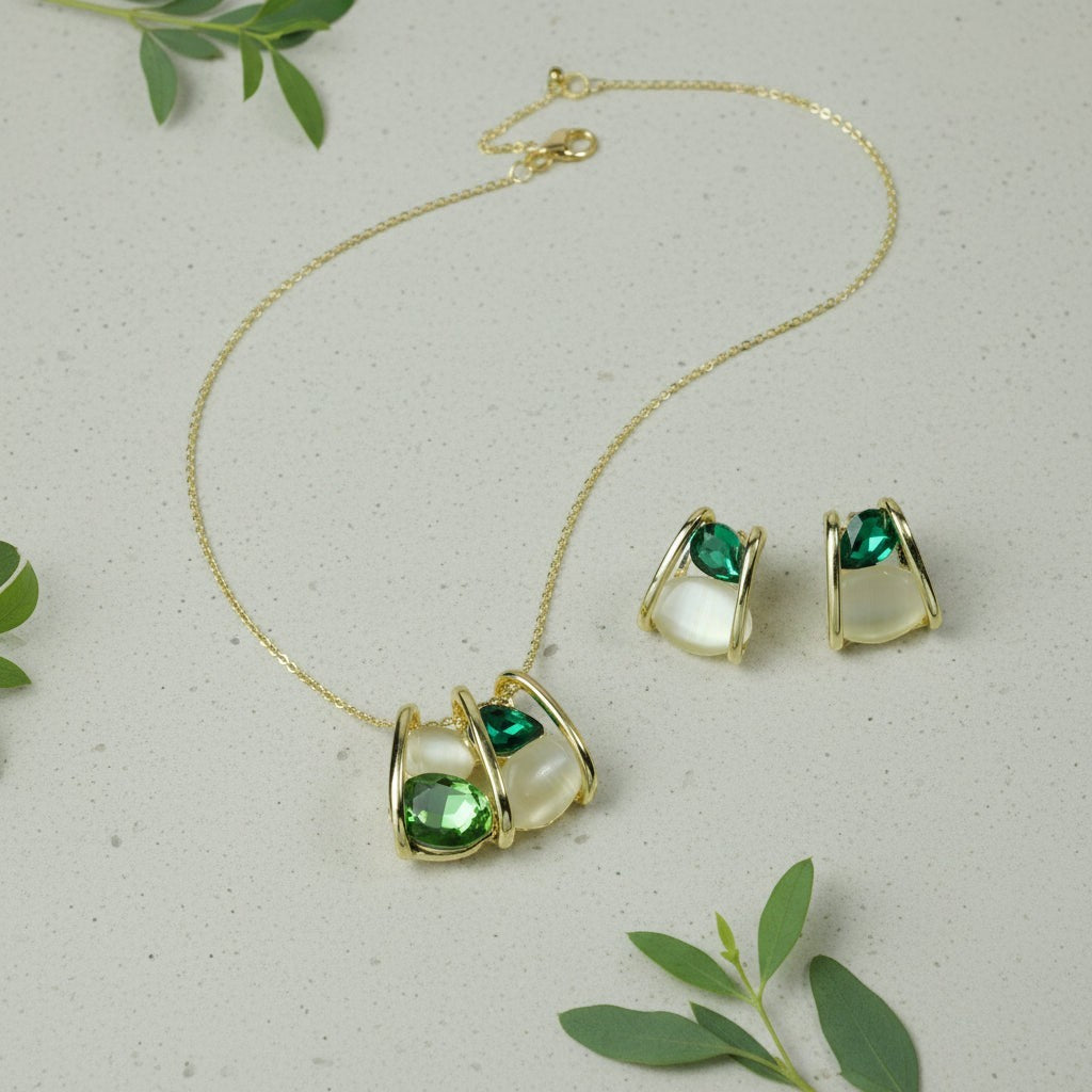 SVORA gold-tone necklace and earrings set with emerald green faceted stones and cream cabochons in a caged design.