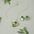 SVORA gold-tone necklace and earrings set with emerald green faceted stones and cream cabochons in a caged design.