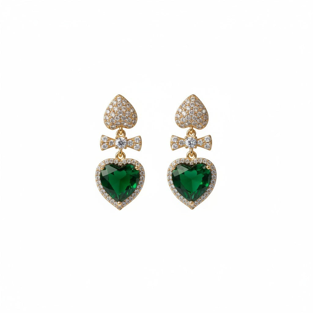 SVORA gold tone drop earrings with emerald crystal heart, pavé bow, and heart stud.